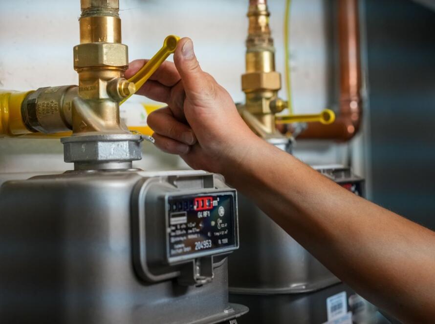 A technician adjusting a gas meter during heating pump maintenance.