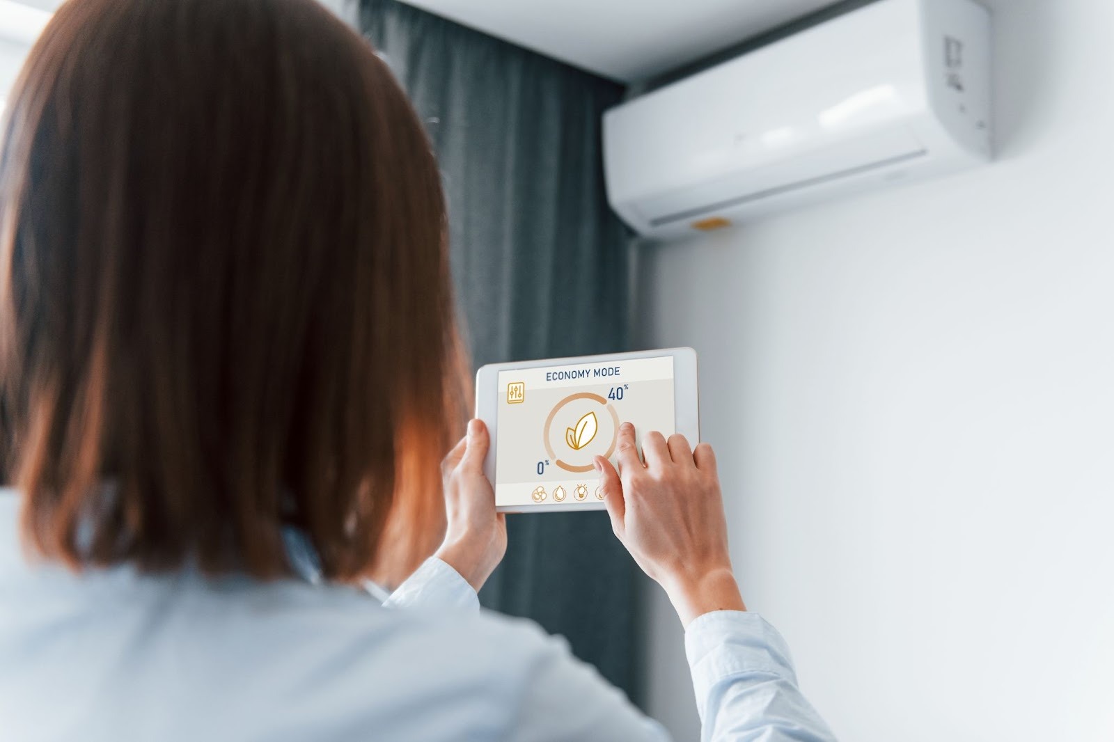 A woman is controlling an air conditioning unit with her tablet.